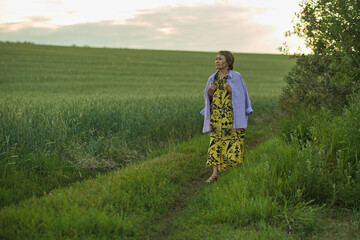 The gentle smile of a mature woman outdoors at sunset. Highlights the growing focus on nature's role in enhancing quality of life for the aged.