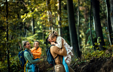 Smiling family of four enjoying hiking in trough forest.