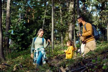 Smiling family of four enjoying hiking in trough forest.