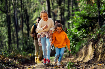 Naklejka na ściany i meble Smiling family of four enjoying hiking in trough forest.