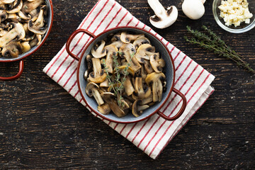Delicious mushrooms cooked with garlic and thyme, on wooden background, flat lay with space for text
