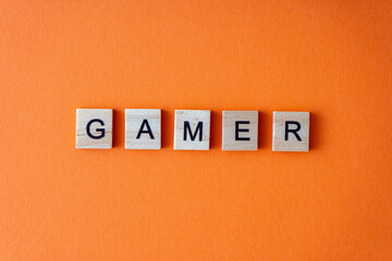 Gamer word. The phrase is laid out in wooden letters top view. Orange flat lay background