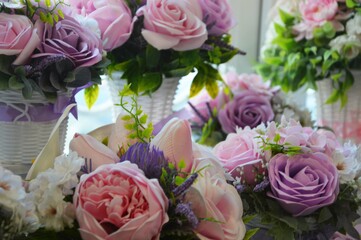 Floral arrangement of pink and lilac peonies and roses with green leaves in white vases. Beautiful floral background.
