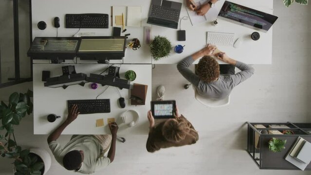 Top view of multiethnic young creative team of software developers program coding and brainstorming while working together in modern open space office