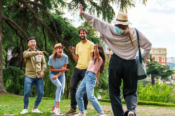 Group of happy friends enjoying a theatrical moment in a city park, surrounded by greenery.