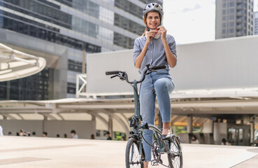 Smart businesswoman wear safety helmet ride bicycle in downtown smile. Environmentalist cycling to...