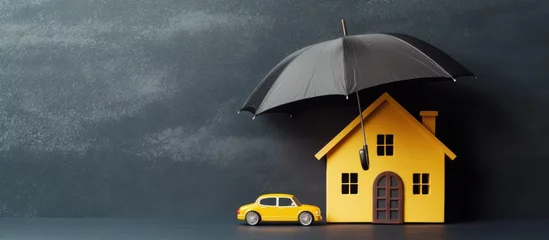 Fotobehang Insurance protects properties like cars and homes depicted as paper cutouts under a yellow umbrella on a blackboard background Copy space image Place for adding text or design © Ilgun
