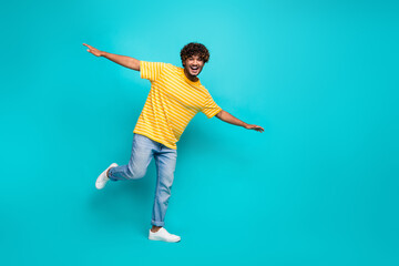 Fototapeta na wymiar Full body photo of attractive young man fly hands wings have fun dressed stylish striped yellow clothes isolated on cyan color background
