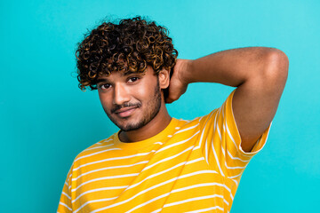Photo of attractive positive young man arm touch hair curly hairstyle isolated on teal color...