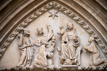 Fototapeta na wymiar Vista del tímpano con la escena de la adoración de los Reyes Magos en el arco gótico de entrada a la iglesia de Ujué, Navarra, España.