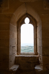 Vista de una ventana con arco gótico y asientos en piedra en la iglesia medieval de Ujué,...