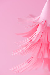 Christmas tree made from pink paper on a pink background, closeup, selective focus.