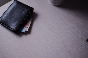 Wallet with a glimpse of banknotes, casually placed on a table, capturing a moment of financial...
