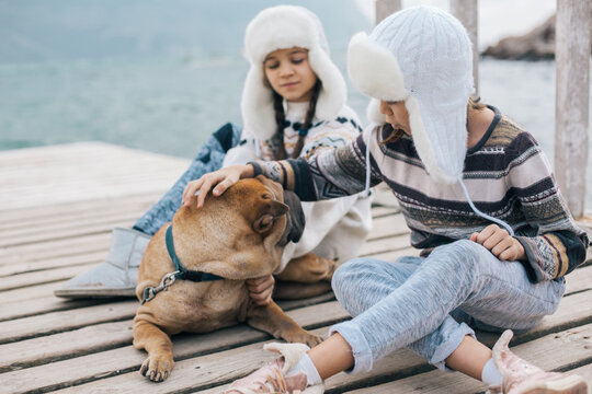 Children travelling with dog in warm wool sweaters and winter hats.
