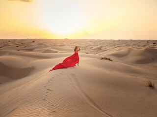 Woman in sands dunes of desert at sunset