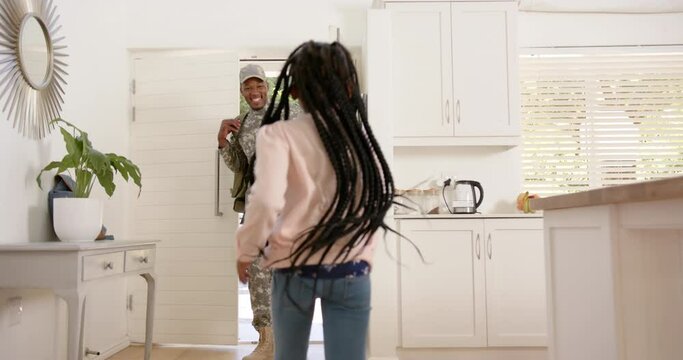 Happy african american male soldier embracing his daughter at home, slow motion