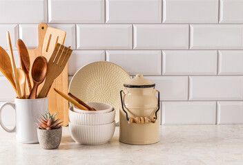 Eco-friendly kitchen utensils on a light stone countertop against a white brick wall. A copy of the...