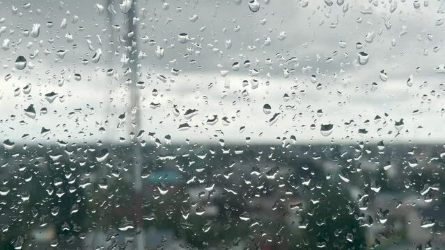 Video of a glass with raindrops on a gray afternoon in the building.