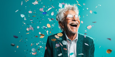 Happy laughing senior man grandad grandfather grandpa with glasses and falling confetti on teal blue background. Modern old guy with smile celebrating at party.