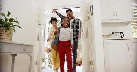 Happy african american parents and daughter coming home from school, slow motion