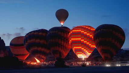 Preparation of hot air balloons at dawn. They are multicolored, illuminated by the fire inside....