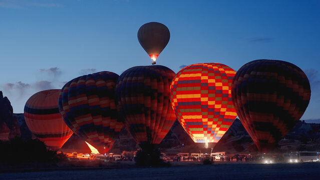 Preparation of hot air balloons at dawn. They are multicolored, illuminated by the fire inside. People are getting ready to ascend into the sky.
