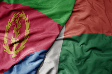 big waving national colorful flag of eritrea and national flag of madagascar .
