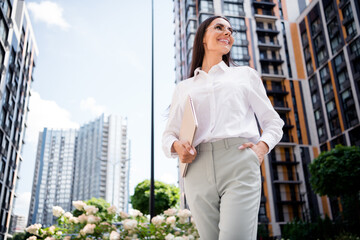 Photo of adorable cheerful lady wearing stylish white shirt walking city center enjoying free time after work summer holidays weekend