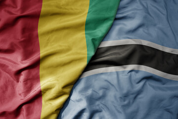 Fototapeta premium big waving national colorful flag of guinea and national flag of botswana .
