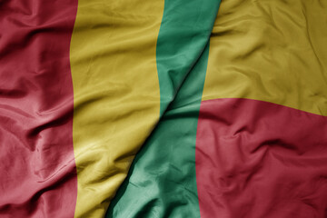 big waving national colorful flag of guinea and national flag of benin .