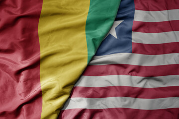 big waving national colorful flag of guinea and national flag of liberia .
