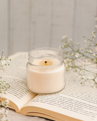 VELA EM CENARIO DELICADO FLORES E LIVRO