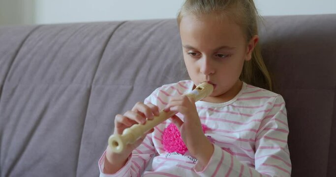 Little girl practice playing the flute at home
