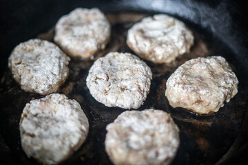 Raw cutlets are fried in a frying pan