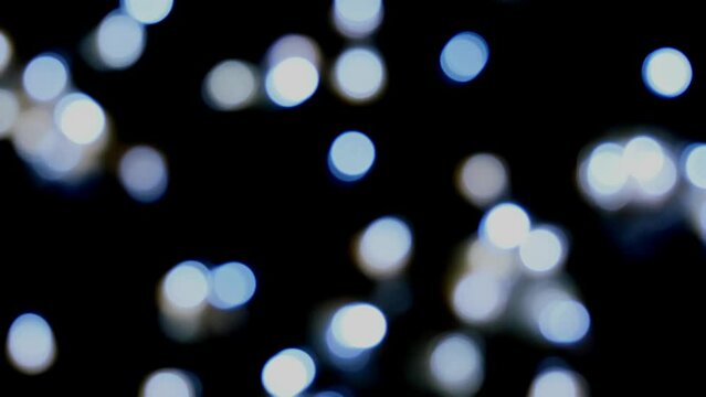 Footage defocused blurry zoom motion of white blinker lights bokeh of Christmas and New year decoration lights, abstract, dark background, overlay for party, shallow DOF