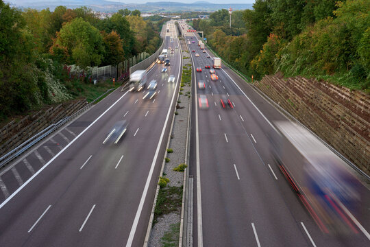 Night lights from car headlights on roundabout in night city. Traces of headlights on the road at night, long exposure. Drone aerial shot. Panoramic aerial view of illuminated road overpass and road
