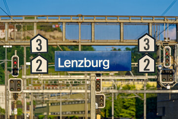 Blue and white sign at railway station at City of Lenzburg on a sunny late spring evening. Photo taken June 11th, 2023, Lenzburg, Switzerland.