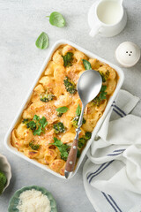 Pasta Broccoli casserole. Baked Mac and cheese with broccoli, cream sauce and parmesan on gray light concrete table background. Healthy or baby food. American Casserole Top view. Copy space.