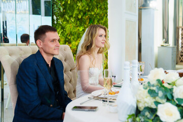 Happy bride and groom at banquet table in restaurant. 