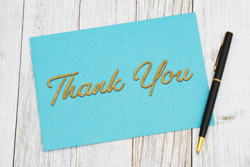 Thank you greeting blue card and pen on wood