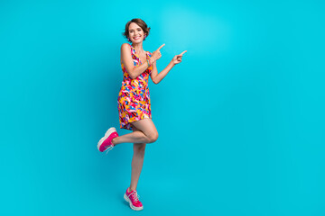 Full size photo of positive cute woman dressed colorful clothes directing at proposition empty space isolated on blue color background