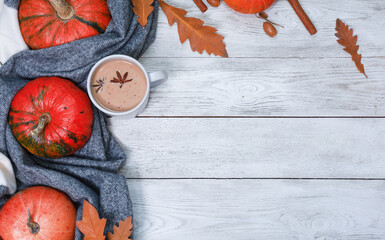 Spicy autumn latte coffee at warm soft cozy scarf, orange pumpkins, spices on thanksgiving wooden white table. Top view with rustic background and copy space