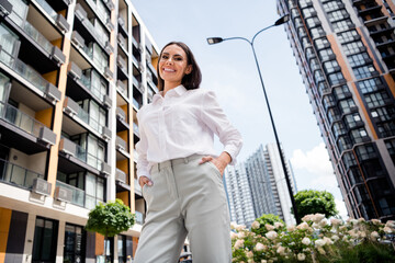 Photo of charming pretty lady realtor wear white shirt spectacles walking new residential complex...