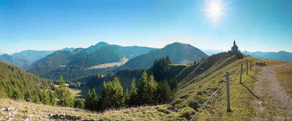 beautiful alpine panorama at Wallberg summit, with view to chapel, bright sun