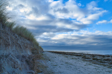 on the beach with dune on the Baltic Sea. Cloudy sky. Waves meet sand. Landscape