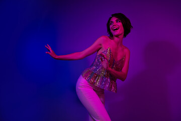 Photo of positive cheerful lady dancing energetic in futuristic night club on neon ultraviolet illumination isolated background