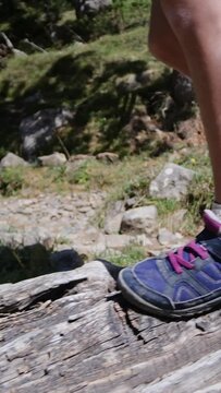 A child balances on a fallen tree by a mountain lake in a U.S. national park. Close-up of legs and boots Adventure, growth, childhood nature connection, eco-education Overcoming challenges and growing
