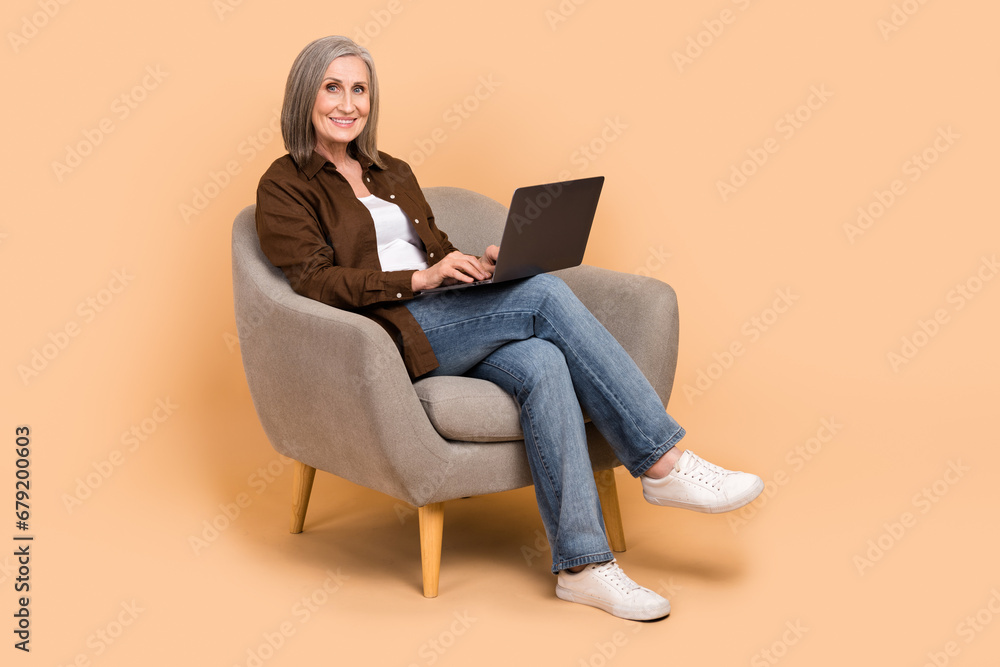 Sticker Full body size photo of sit comfort armchair woman grandmother learning new device modern netbook isolated over beige color background