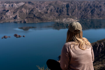 Fototapeta na wymiar young woman with open arms in a landscape of mountains and free lake on a clear sunny day