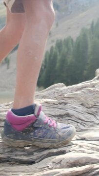 A boy walks on a fallen tree trunk near a mountain lake in a U.S. national park. Detail of legs and boots Adventure, growth, childhood nature connection, environmental education. Overcoming challenge
